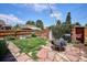 Landscaped backyard featuring a stone patio, green lawn, outdoor seating, string lights, and a charming garden area at 3622 Lowell Blvd, Denver, CO 80211