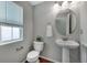 Bathroom featuring hardwood floors, a pedestal sink, a round mirror, and a toilet with blinds at 1416 Red Mica Way, Monument, CO 80132