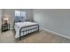 Bedroom with neutral walls and carpet, large window, iron bed frame with white comforter, and dark side table at 1416 Red Mica Way, Monument, CO 80132