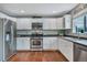 Well-lit kitchen featuring stainless steel appliances, white cabinetry, and beautiful hardwood floors at 1416 Red Mica Way, Monument, CO 80132