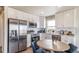 Bright kitchen with white cabinets, stainless steel appliances, and a cozy dining area for enjoyable meals at 13586 E 103Rd Pl, Commerce City, CO 80022