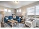 Cozy living room featuring a comfortable blue L-shaped sofa, armchair, and a large window with outdoor view at 13586 E 103Rd Pl, Commerce City, CO 80022