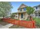 Inviting two-story home features a classic design and colorful red fence enhancing its curb appeal at 2538 Central Park Blvd, Denver, CO 80238