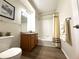 Well-lit bathroom featuring a tub with shower, wood vanity, neutral walls and flooring, with stylish fixtures at 4451 S Ammons St # 108, Littleton, CO 80123