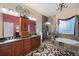 Luxurious bathroom with dual sinks, granite countertops, a walk-in shower, and a soaking tub under a window at 5118 Bottlebrush Run, Broomfield, CO 80023