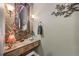 Stylish powder room with a unique glass bowl sink, ornate mirror, decorative lighting, and travertine tile at 5118 Bottlebrush Run, Broomfield, CO 80023