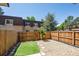 Private backyard with a wooden fence, artificial turf, a decorative rock garden, and a small sapling tree at 7755 E Quincy Ave # T2, Denver, CO 80237
