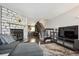 Warm living room featuring a stone fireplace, hardwood floors, and open layout with views into the kitchen at 2594 E Nichols Cir, Centennial, CO 80122