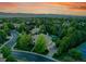 Stunning aerial view of a tree-lined neighborhood highlighting the manicured property with tennis and basketball courts at sunset at 291 Fairchild Dr, Highlands Ranch, CO 80126