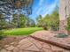 Expansive backyard featuring lush lawn, mature trees, and a stone patio, perfect for outdoor living at 291 Fairchild Dr, Highlands Ranch, CO 80126