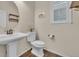 Well-lit powder room with a pedestal sink, round mirror, and a window with plantation shutters at 3762 White Rose Loop, Castle Rock, CO 80108