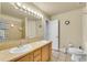 Bathroom featuring a double sink vanity, tiled shower and a neutral color palette at 6943 Saddleback Ave, Firestone, CO 80504