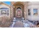 Close-up of a home's entryway featuring a stone archway, burgundy front door, and decorative planters at 6943 Saddleback Ave, Firestone, CO 80504