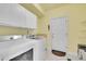Functional laundry room with white cabinets, washer, dryer, and access to the exterior at 6943 Saddleback Ave, Firestone, CO 80504