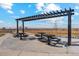 Community picnic area featuring multiple tables with attached seating, sheltered by a pergola, and a serene landscape view at 2214 Alyssa St, Fort Lupton, CO 80621