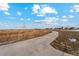 Concrete walking path winds through a field toward community homes under a partly cloudy, bright blue sky at 2214 Alyssa St, Fort Lupton, CO 80621