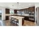 Modern kitchen with dark wood cabinets, stainless steel appliances, and a large marble island with seating at 22268 E Hidden Trail Dr, Parker, CO 80138