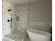 Modern bathroom featuring marble tile, large shower, soaking tub, and black fixtures at 13350 Imboden Rd, Hudson, CO 80642