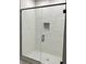 Modern shower with glass door, white tile with a textured wall, and a mosaic tile base at 13350 Imboden Rd, Hudson, CO 80642
