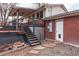 Backyard exterior featuring brick siding, a wooden deck with stairs, and a small stepping stone walkway at 889 Douglas Dr, Denver, CO 80221