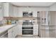 Bright kitchen featuring stainless steel appliances, white cabinets, and tiled backsplash at 4713 S Robb St, Littleton, CO 80127