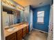 Bright bathroom with double sink vanity, framed mirror, decorative accents, and a tiled floor at 15523 E 117Th Ave, Commerce City, CO 80022