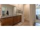 Bright bathroom with dual sink vanity featuring granite counters and wood cabinets and view of bedroom at 22820 E Chenango Ave, Aurora, CO 80015