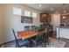 Dining area featuring a wooden table with seating for six, bright lighting, and adjacent kitchen at 22820 E Chenango Ave, Aurora, CO 80015