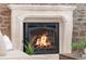 Close up of a cozy stone fireplace with a metal grate, and a flickering fire at 3143 Elmira St, Denver, CO 80238