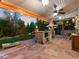 Inviting covered outdoor kitchen featuring stone accents, built-in grill, and stylish lighting for evening entertaining at 7668 S Locust St, Centennial, CO 80112