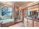 Updated bathroom with stone-tiled shower, soaking tub, vanity, and window with natural light at 31190 Cinnamonwood, Evergreen, CO 80439