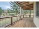 Covered deck with wooden floors, offering a serene outdoor living space among the trees at 31190 Cinnamonwood, Evergreen, CO 80439