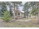 Beautiful home exterior with stone accents and landscaped surroundings with mature trees, blending with nature at 31190 Cinnamonwood, Evergreen, CO 80439