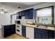 Kitchen with navy cabinets, white appliances, and a view into an adjoining room at 460 Lansing St, Aurora, CO 80010