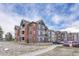 View of the multi-Gathering apartment building with brick and siding exterior, parking lot, and well-maintained landscaping at 14333 E 1St Dr # 307, Aurora, CO 80011