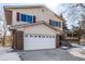 Well-maintained two-story home featuring a brick and siding exterior with a two-car garage and a snowy yard at 2290 S Braun Way, Lakewood, CO 80228