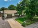 Aerial view of a single-story home featuring a brick facade, attached garage, long driveway, and established landscaping at 7936 Eaton St, Arvada, CO 80003