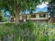 Charming single-story home featuring a brick facade, attached garage, and mature landscaping with bright colored flowers at 7936 Eaton St, Arvada, CO 80003