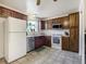 Traditional kitchen with warm wood cabinetry, white appliances, tile floors and a view to the outside at 7936 Eaton St, Arvada, CO 80003