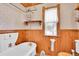 Quaint bathroom featuring a clawfoot tub, wood paneling, and decorative wallpaper at 1918 Virginia St, Idaho Springs, CO 80452