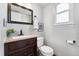 Bathroom with dark wood vanity, framed mirror, toilet, and window, offering a clean and functional space at 5207 S Jericho Way, Centennial, CO 80015