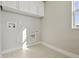 Well-lit laundry room with tile flooring, white cabinets, and hookups for washer and dryer at 1622 W 67Th Ave, Denver, CO 80221