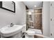 This bathroom features tiled walk-in shower with glass door, tile flooring, pedestal sink and modern toilet at 7511 S Sicily Way, Aurora, CO 80016