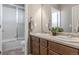 Bright bathroom featuring a double sink vanity, and a shower-tub combo with sliding glass door at 18875 W 93Rd Ave, Arvada, CO 80007