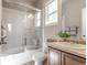 Bright bathroom featuring a shower-tub combo with sliding glass door, a window and a vanity with updated sink at 18875 W 93Rd Ave, Arvada, CO 80007