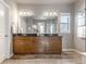 Bathroom showcasing a large mirror over a double vanity with wood cabinets, a window, and a separate glass-enclosed shower at 18875 W 93Rd Ave, Arvada, CO 80007