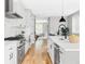 Open-concept kitchen with white cabinets, stainless steel appliances, and hardwood flooring at 1541 Glencoe St, Denver, CO 80220