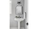 Elegant powder room featuring pedestal sink, arched mirror and modern lighting at 1541 Glencoe St, Denver, CO 80220