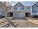 View of a two-story townhome with gray siding, complemented by a spacious driveway and attached one-car garage at 1303 S Danube Way # 104, Aurora, CO 80017