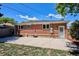 Home exterior featuring a brick facade, concrete patio, grassy yard, and privacy fence at 1852 S Decatur St, Denver, CO 80219